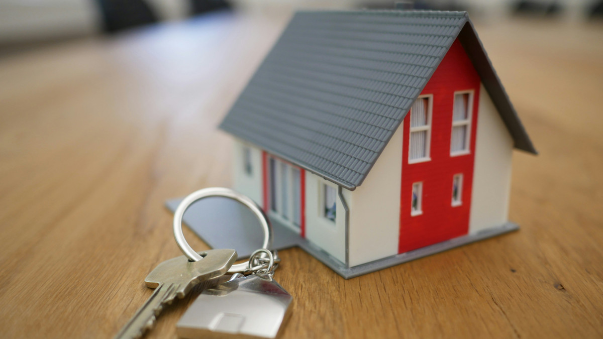 concept d'acquisition d'un bien immobilier représenté par une petite maison avec clés sur le côté